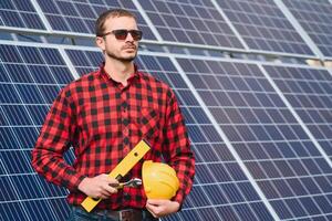 joven técnico instalando solar paneles en fábrica techo foto