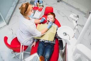 pediátrico dentista examinando un pequeño Niños dientes en el dentistas silla a el dental clínica foto