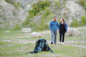 Couple enjoying beautiful views on the mountains, while traveling with backpacks in the mountains during the summer vacations photo