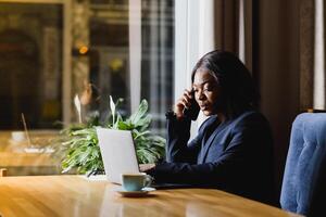 Pensive black businesswoman using tablet computer in coffee shop photo