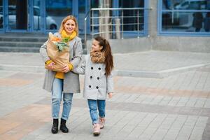 familia compras. madre y su hija son participación tienda de comestibles compras bolso con vegetales. foto