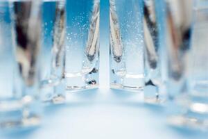 Line of glasses, a glass with water, on a light blue background. Difference concept. Equality concept. photo
