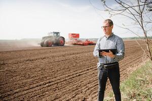 farmer on background of tractor sowing field. Work in the field. Agriculture concept. Farm work in the field in spring photo