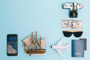 top view travel concept with retro camera films, smartphone, map, passport, compass and Outfit of traveler on blue background with copy space, Tourist essentials, vintage tone effect photo