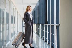 elegante mujer de negocios con equipaje a el aeropuerto. el concepto de negocio vuelos por avión foto