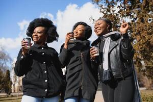 elegante africano americano muchachas Bebiendo café en el calle foto