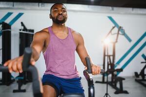 africano hombre utilizando estacionario bicicleta en un gimnasio foto