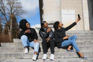 elegante africano americano muchachas Bebiendo café en el calle foto