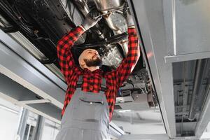 mecánico trabajando debajo coche a el reparar cochera. auto mecánico trabajando en cochera. reparar servicio. foto