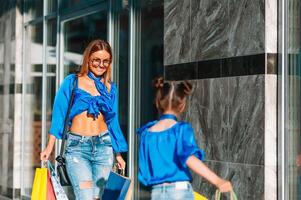 sale, consumerism and people concept - happy young women her dauther with shopping bags walking city street photo