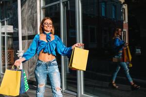 sonriente joven mujer posando con un puñado de compras pantalones foto