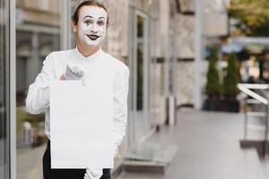 Your text here. Actor mime holding empty white letter. Colorful portrait with gray background. April fools day photo