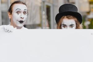 Your text here. Actors mimes holding empty white letter. Colorful portrait with gray background. April fools day photo