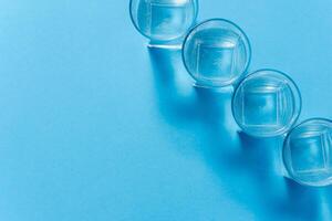 Line of glasses, a glass with water, on a light blue background. Difference concept. Equality concept. photo