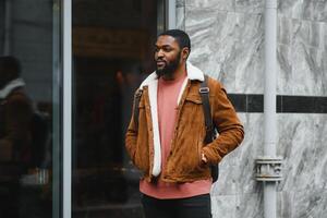 portrait of confident trendy serious african guy in stylish outfit, young afro american male posing at camera, looking away photo