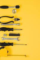 Tools top view on yellow background. Plier, open wrenches, screwdrivers and staple gun flat lay with copy space photo