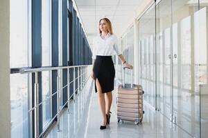 retrato de exitoso negocio mujer de viaje con caso a aeropuerto. hermosa elegante hembra viaje con equipaje. foto