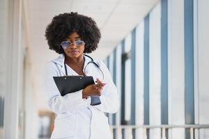 de cerca disparo a la cabeza retrato de amigable, sonriente confidente hembra cuidado de la salud profesional con laboratorio abrigo, brazos cruzado participación lentes. aislado hospital clínica antecedentes. hora para un oficina visitar foto