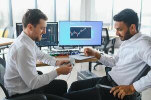 Two diverse crypto traders brokers stock exchange market investors discussing trading charts research reports growth using pc computer looking at screen analyzing invest strategy, financial risks. photo