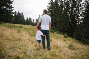 Father and child hiking in scenic mountains. Dad and son enjoying the view from the mountain top in Carpathian mountains photo