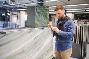 man choosing ceramic tiles and utensils for his home bathroom photo