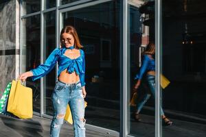 sonriente joven mujer posando con un puñado de compras pantalones foto