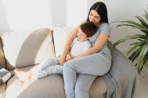 Mother playing with her little cute son in the morning in bedroom. Happy family time. photo