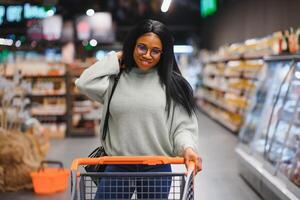 African american woman at supermarket with shopping cart photo