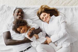 Family laying down together in a bed photo