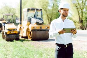 engineer near road machinery. The concept of building a new asphalt road. Road repair. Road service worker near the rink. photo