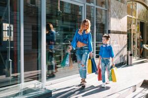venta, consumismo y personas concepto - contento joven mujer su hija con compras pantalones caminando ciudad calle. foto