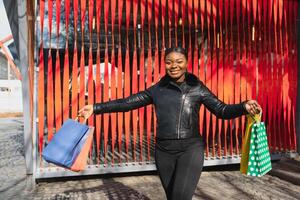 Attractive young African-American woman shopping - shopping bags, outdoors, street view, suitable for holiday shopping themes, among others photo