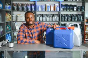 seller man with canister of motor oil in auto store photo
