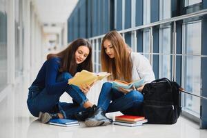 hembra estudiantes sentado en el piso y leyendo notas antes de examen foto