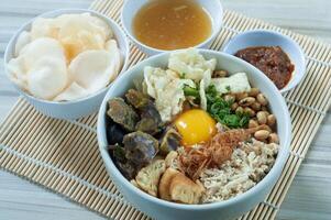 Bubur Daging Spesial or Special Meat Porridge contains white rice with side dishes of grilled beef slices photo