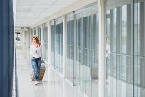 Girl traveler walking with carrying hold suitcase in the airport. Tourist Concept. Woman walks through airport terminal with luggage. travel concept photo