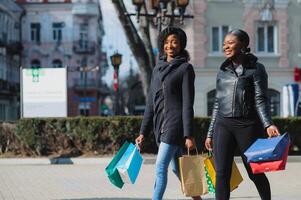 Two afro american women friends in the city on a shopping trip carrying colorful shopping bags. photo