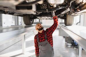 Mechanic working under car at the repair garage. Auto mechanic working in garage. Repair service. photo