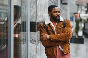 portrait of confident trendy serious african guy in stylish outfit, young afro american male posing at camera, looking away photo