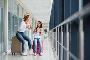 mujer con pequeño niña en internacional aeropuerto. madre con bebé esperando para su vuelo. de viaje con niños foto