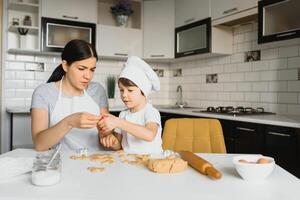 pequeño chico Ayudar su madre con el horneando en el cocina en pie a el mostrador junto a su amasadura el masa para el tarta foto