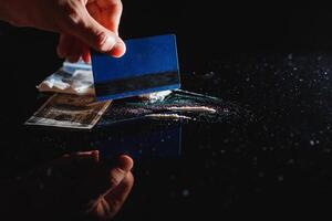 Close up of hands of young druggie is doing tracks of cocaine with a credit card. photo