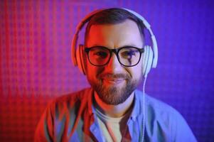 Neon portrait of bearded smiling man in headphones, glasses photo