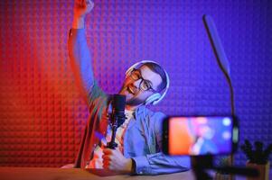 A video blogger records content in his studio. The host of the video blog is a young man who is very enthusiastic about telling his subscribers a story. photo