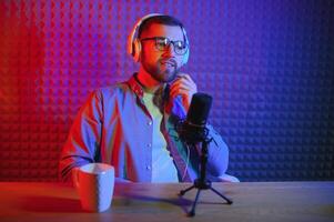 Young man recording or streaming podcast using microphone at his small broadcast studio. Content creator. photo