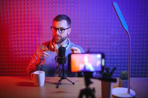 Young man recording or streaming podcast using microphone at his small broadcast studio. Content creator. photo