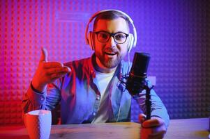 Young man recording or streaming podcast using microphone at his small broadcast studio. Content creator. photo