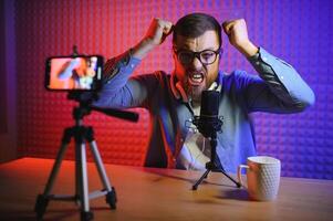 Young man recording or streaming podcast using microphone at his small broadcast studio. Content creator. photo