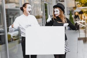 Your text here. Actors mimes holding empty white letter. Colorful portrait with gray background. April fools day photo