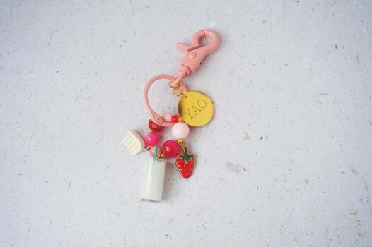 Bottle of milk and strawberry attached to pink key chain on white background. Top view. photo